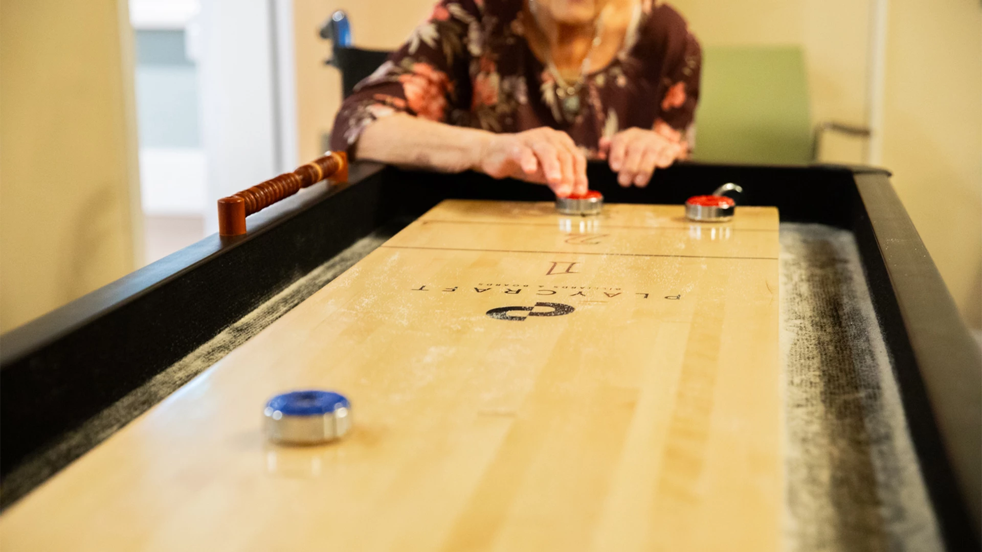 Female senior sliding a red a shuffle board piece